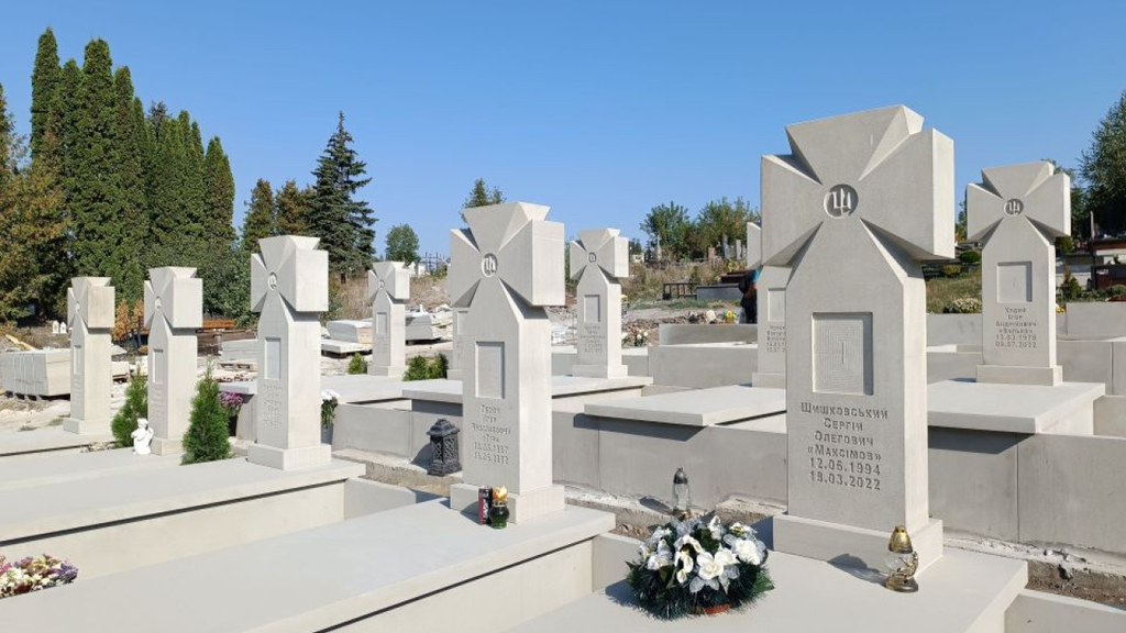 Світлі кам’яні надгробки у формі козацького хреста з тризубом на військовому кладовищі