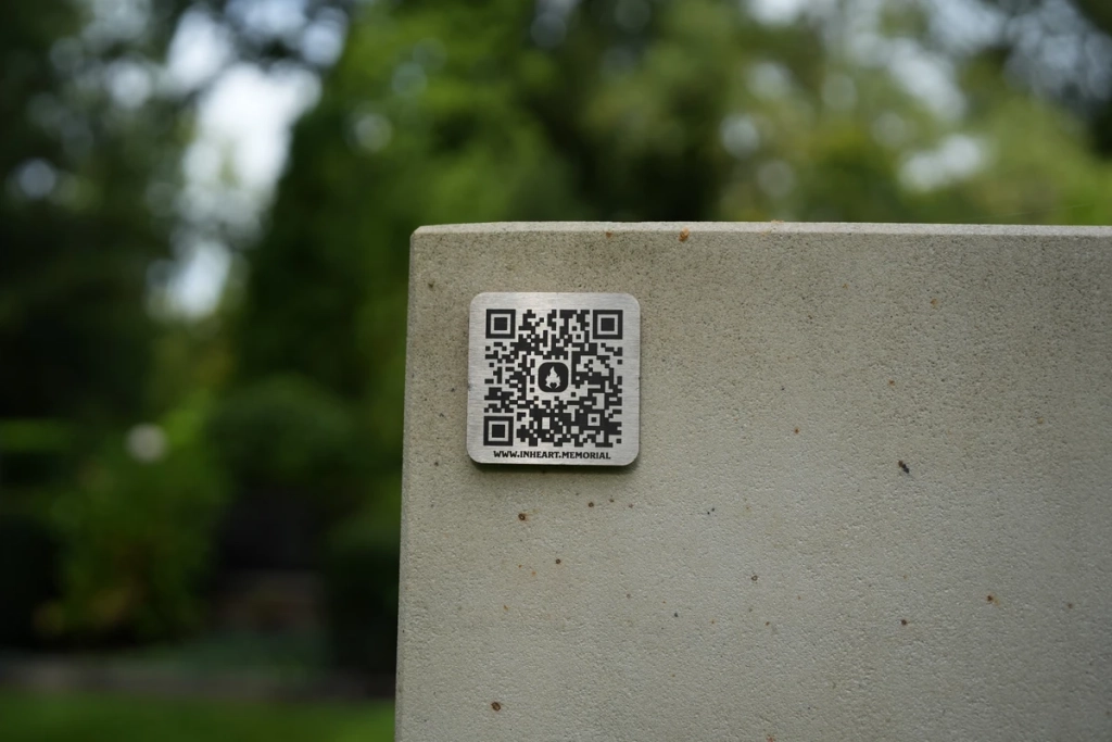 Металевий QR-медальйон Inheart на світлій кам’яній поверхні.